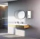 Weißer Durchlauferhitzer von Stiebel Eltron an der Wand, daneben Doppelwaschbecken mit zwei Wasserhähnen, moderner Spiegel über dem Waschbecken.